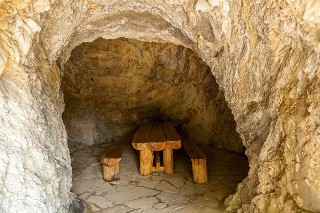 Tavolo in legno con due panche in una stanza in pietra. Stanze di pietra della Georgia.viaggio in Georgia