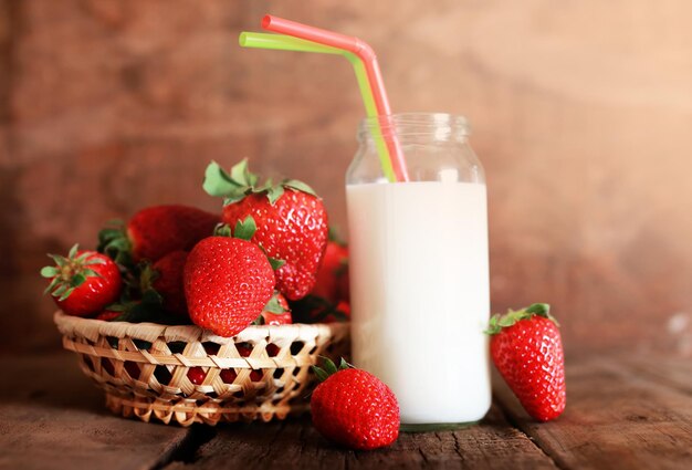 Tavolo in legno con fragole e latte in un bicchiere