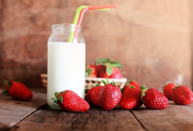 Tavolo in legno con fragole e latte in un bicchiere