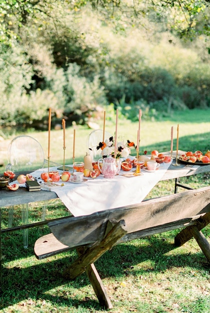 Tavolo in legno con frutta e candele si trova in un giardino verde