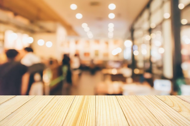 Tavolo in legno con ristorante, caffè o caffetteria interno con persone sfondo sfocato astratto sfocato