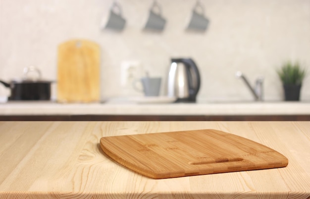 Tavolo in legno con tagliere su uno sfondo sfocato della cucina spazio vuoto per il layout del prodotto