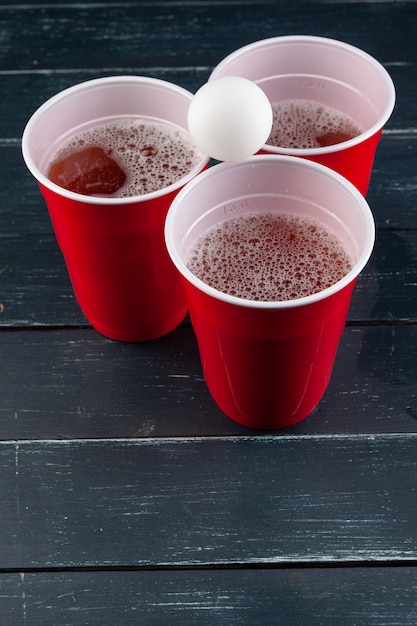 Tavolo in legno con tazze rosse e palla per birra pong
