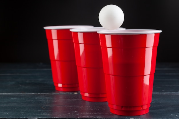 Tavolo in legno con tazze rosse e palla per birra pong