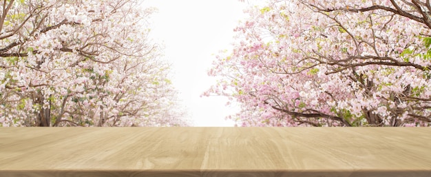 Tavolo in legno e albero di fiori sfocato sfondo parco banner - può essere utilizzato per la visualizzazione o il montaggio dei vostri prodotti.