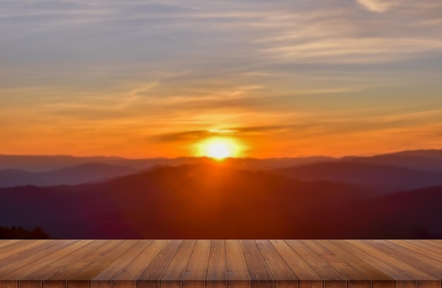 Tavolo in legno e sfocatura di bellezza, cielo al tramonto e montagne come sfondo.