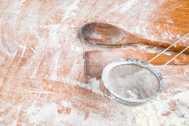 tavolo in legno infarinato con utensili da cucina. sfondo della cucina