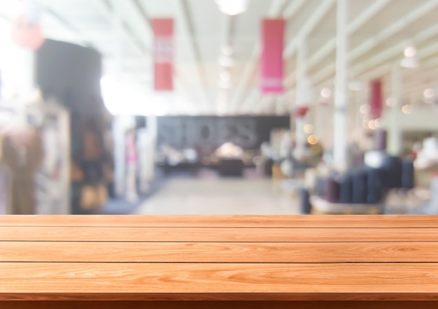 Tavolo in legno nel centro commerciale o nel grande magazzino sfocatura dello sfondo con lo spazio vuoto della copia sul tavolo
