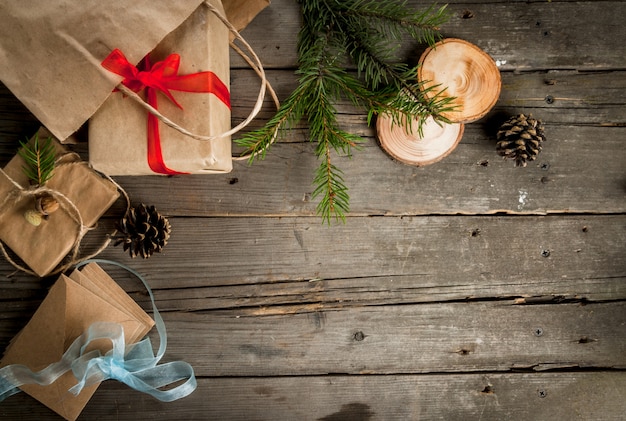 Tavolo in legno rustico, confezioni regalo per Natale, coni, rami e decorazioni natalizie sul tavolo. Vista dall'alto, copia spazio