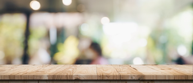 Tavolo in legno vuoto e tavolo luminoso sfocato in caffetteria e bar con sfondo bokeh. modello di visualizzazione del prodotto.