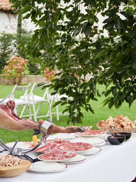 Tavolo per antipasti di nozze con pane al prosciutto iberico appena tagliato e pomodoro Tipiche tapas spagnole servite all'esterno