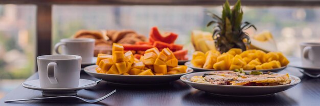 Tavolo per la colazione con caffè, frutta e pane croissant su un balcone sullo sfondo del grande