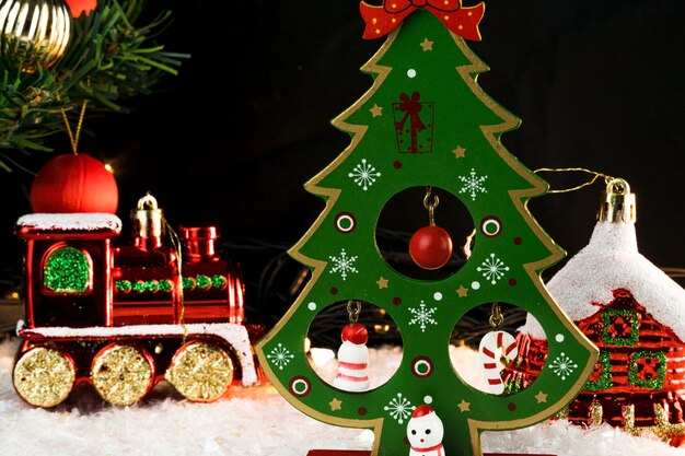 Tavolo ricoperto di fiocchi di neve con decorazioni natalizie. Babbo Natale, albero di Natale con palline rosse e dorate e luci. Messa a fuoco selettiva.