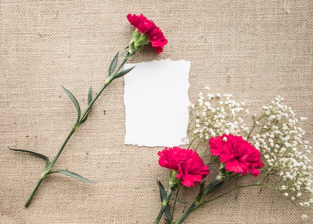 Tavolo scrivania da ufficio con carta da lettere, bouquet di fiori su tela di sacco