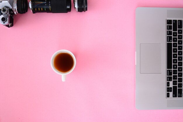 Tavolo scrivania da ufficio con laptop, macchina fotografica e caffè lenti.