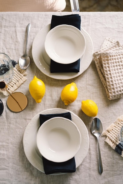 Tavolo vintage con tovaglioli di lino e limoni gialli Tavolo decorativo Primo piano Accogliente pasto tranquillo al mattino sotto il sole