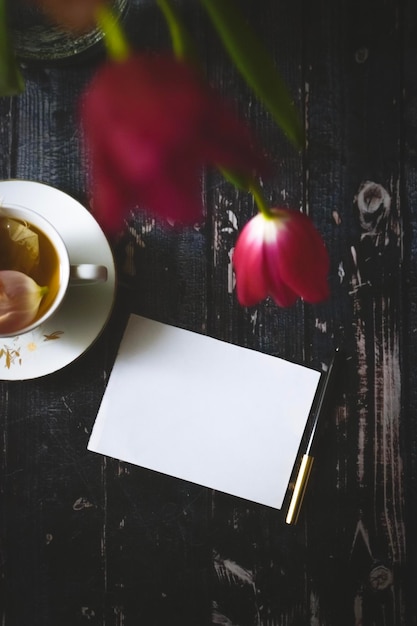 Tazza a T su fondo in legno con tulipani primaverili e foglio bianco