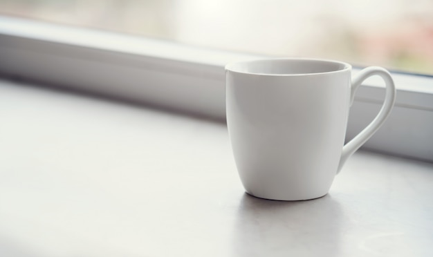 Tazza bianca bianca sul davanzale al mattino