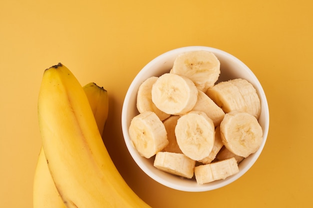 Tazza bianca con banane a fette su un giallo