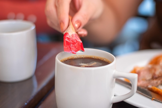 Tazza bianca con bevanda calda al caffè con bustina di ingredienti in polvere