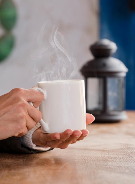 tazza bianca con bevanda calda e mani fumanti che si scaldano dal caldo di casa Concentrati sulla tazza