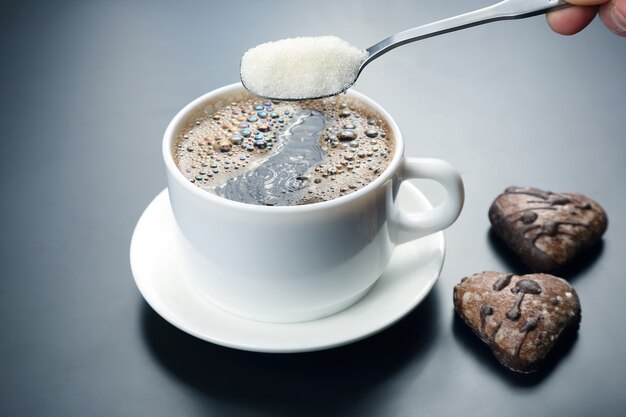 Tazza bianca con caffè nero e cucchiaio con zucchero