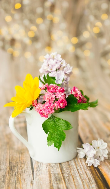 Tazza bianca con fiori colorati su fondo di legno