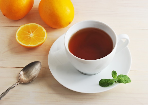 Tazza bianca con tè nero, cucchiaino, limone e menta