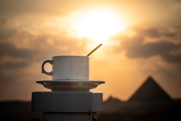 Tazza bianca con tè o caffè su uno splendido sfondo delle principali attrazioni dell'Egitto, le grandi piramidi di Giza