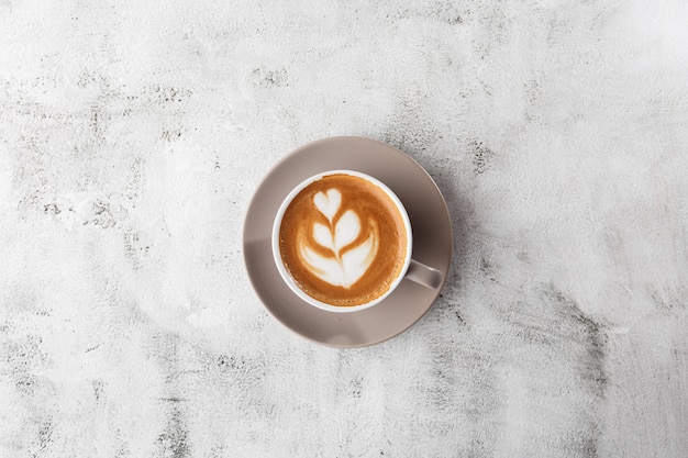 Tazza bianca del caffè caldo del latte con bella struttura di arte del latte della schiuma del latte isolata su fondo di marmo luminoso. Vista dall'alto, copia spazio. Pubblicità per menu bar. Menu della caffetteria. Foto orizzontale.