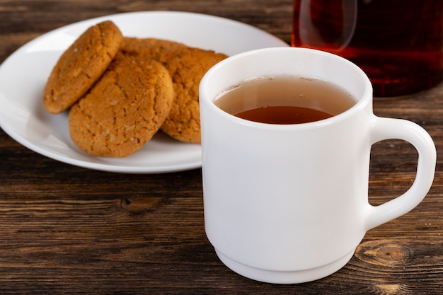 Tazza bianca della porcellana dei biscotti dell'avena e del tè su una tabella