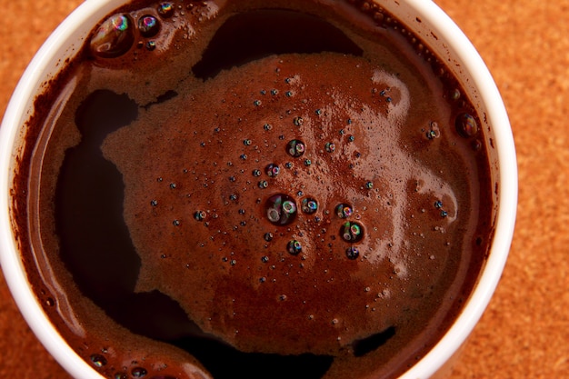 Tazza bianca di caffè nero caldo su un primo piano della tavola del sughero