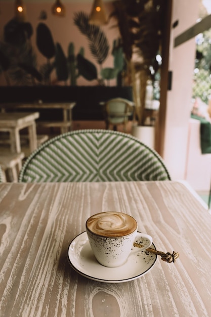 Tazza bianca di cappuccino caldo su sfondo di tavolo in legno chiaro