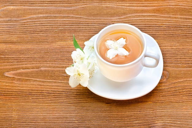 Tazza bianca di tè al gelsomino su una tavola di legno marrone. Primo piano, vista dall'alto