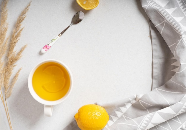 Tazza bianca di tè caldo con limone su uno sfondo di marmo bianco vista dall'alto dell'immagine quadrata