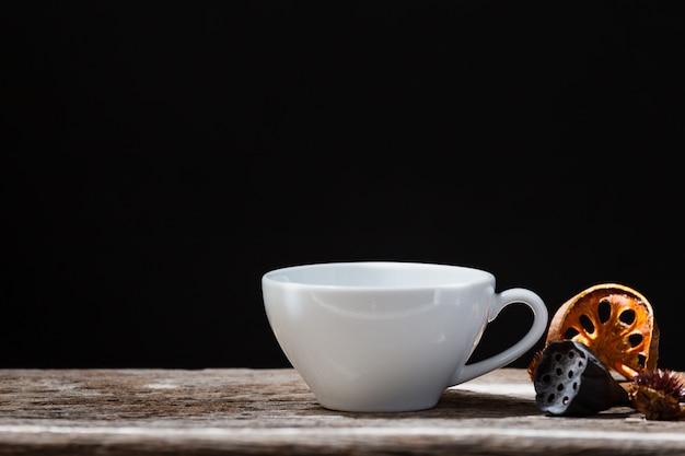 tazza bianca secca cotogne e bastoncini di cannella su fondo di legno scuro