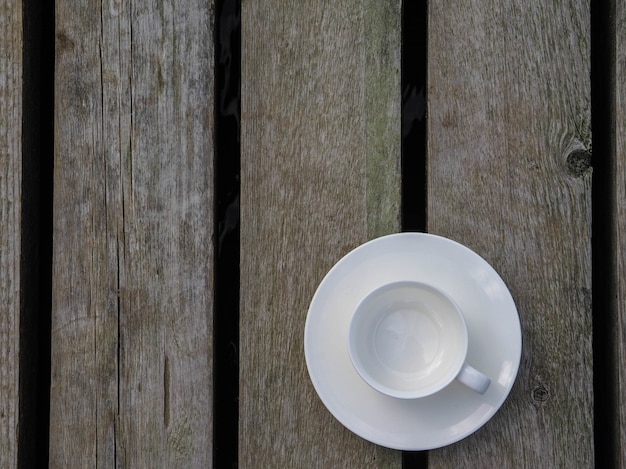 Tazza bianca vuota sul ripiano del tavolo in legno. Copia spazio