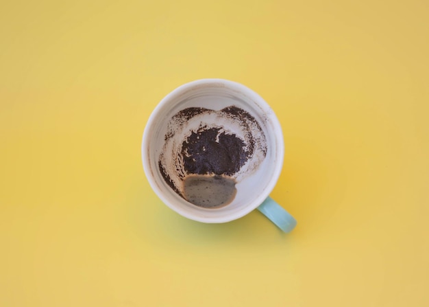 Tazza blu con fondi di caffè su sfondo giallo