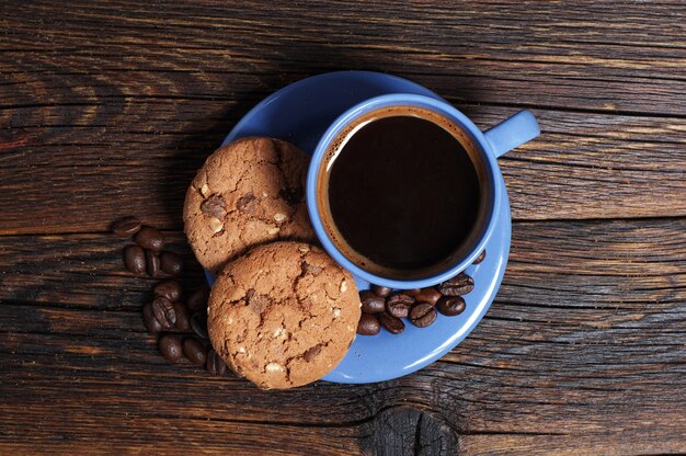 Tazza blu di caffè caldo con biscotti su fondo di legno, vista dall'alto