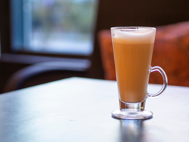 Tazza calda di caffè latte sulla tavola di legno in un interno caldo accogliente