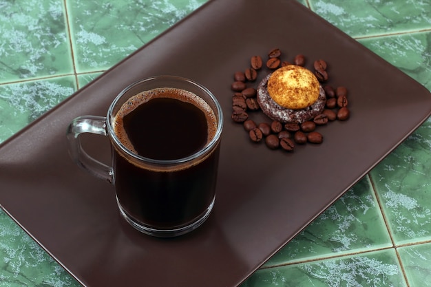 Tazza calda di caffè nero profumato su piattino con biscotti