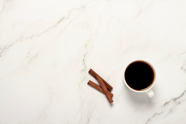 Tazza con caffè e bastoncini di cannella su un tavolo di marmo. Vista piana, vista dall'alto