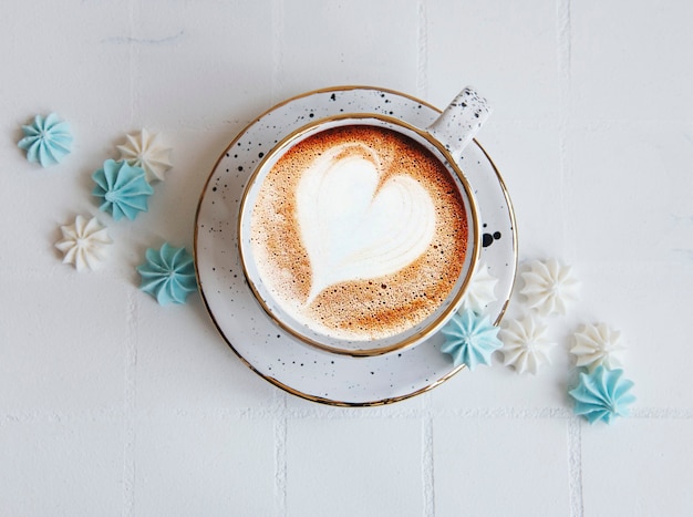 Tazza con caffè e piccole meringhe su fondo piastrellato