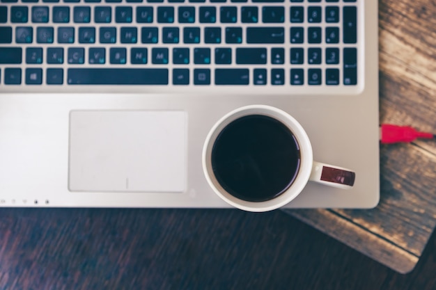 Tazza con caffè mattutino, laptop sul tavolo, concetto di mattina al lavoro