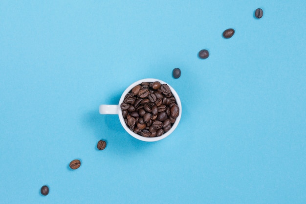 Tazza con chicchi di caffè su una parete colorata