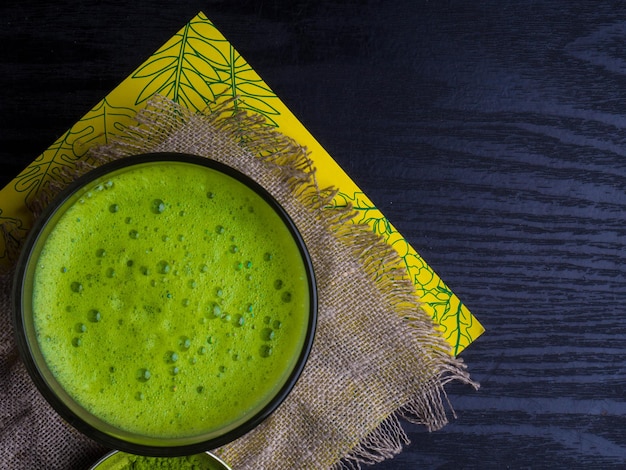 Tazza con latte di tè matcha su fondo di legno nero