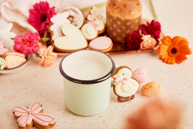 Tazza con latte e biscotti decorati con torta di Pasqua tra fiori Primavera accogliente sfondo estetico