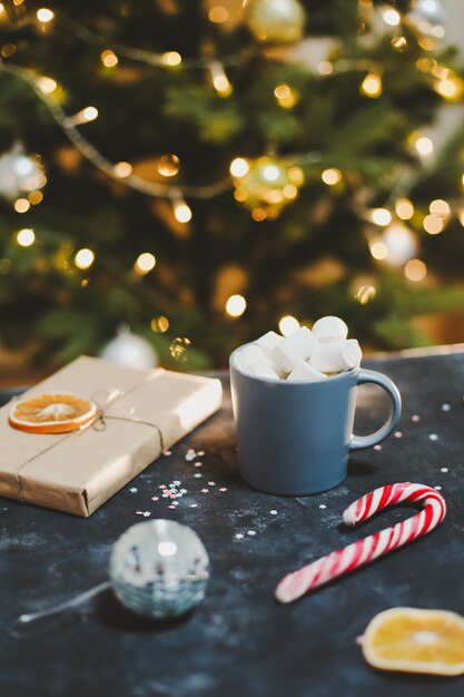 Tazza con marshmallows canna da zucchero mandarini sullo sfondo dell'albero di Natale Anno nuovo ancora vita