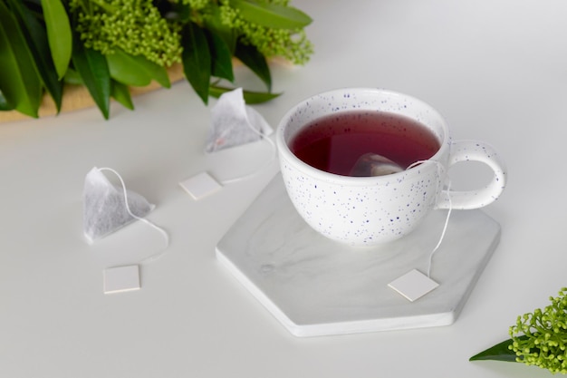 Tazza con tè e set di bustina di tè per infusione triangolare con etichetta su sfondo bianco Spazio per il testo Mockup