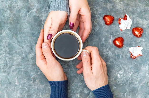 Tazza da bere per la colazione nelle mani degli innamorati. Messa a fuoco selettiva